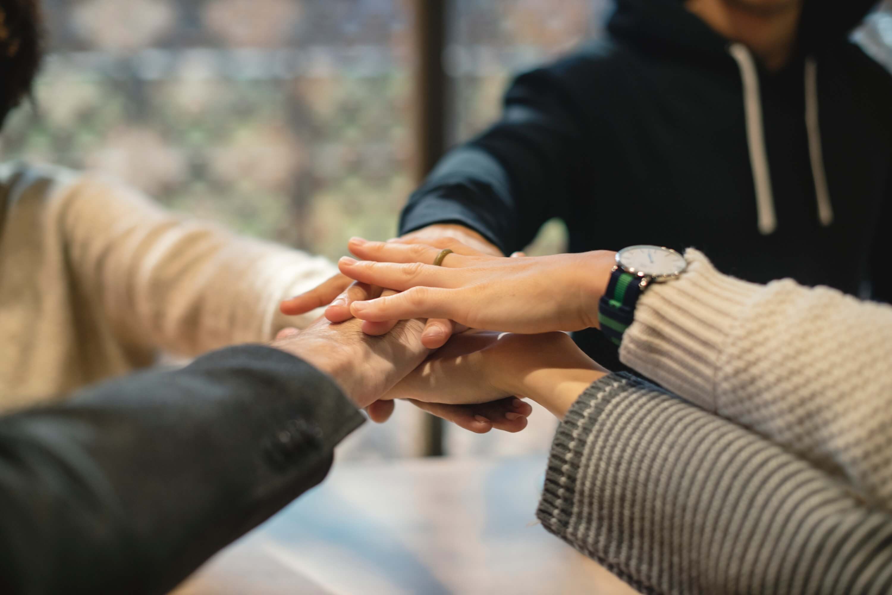 Four people putting their hands on top of each other